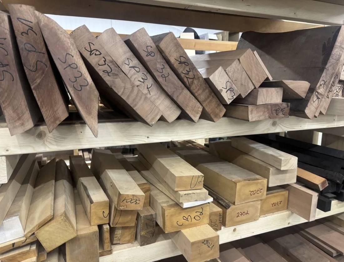 Sorted wood offcuts and blanks on workshop shelves, labelled by species